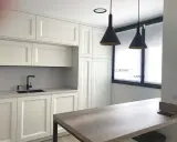 Cocina moderna con armarios blancos, encimera gris, grifo negro y cortinas blancas. Ideas para tu cocina.