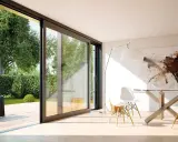 Amplias ventanas aislantes conectan un moderno comedor con un exuberante jardín.