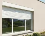 Instalación de persianas enrollables blancas en una casa moderna. El jardín y las colinas se reflejan en los cristales.