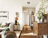 Perro espera en el pasillo que conecta la entrada, salón y recibidor. Mueble antiguo y plantas decoran el espacio.
