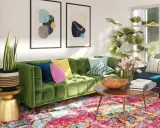 Sofá verde vibrante con cojines coloridos, alfombra persa y arte abstracto. Una sala acogedora, perfecta para una reforma sin obras.