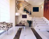 Elegante rellano escalera decoracion con sillones florales y una lámpara de pie. El descansillo escalera cuenta con una barandilla metálica y luces integradas.