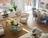 Espacio luminoso con sofás, mesas de centro y una mesa de comedor lista para una comida. La distribución del comedor es funcional y acogedora.