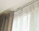 Detalle de rieles para cortinas, mostrando diferentes tipos de tela y su sistema de sujeción al techo.