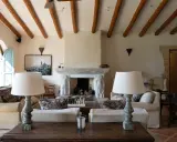 Acogedor salón comedor de casa de campo con vigas de madera, chimenea de piedra y sofás confortables.
