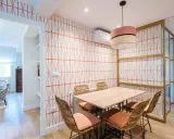Comedor con papel pintado de rombos naranjas, mesa de madera y sillas de mimbre. Un ejemplo de como poner papel pintado para renovar tu hogar.