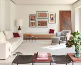 Una composición de cuadros en la pared, con arte abstracto y tipografía, decora este salón moderno junto a un sofá blanco y una butaca gris.