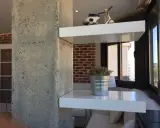 Ideas para decorar una columna en el salón: estantes blancos con Vespa y planta, ladrillo visto y hormigón.