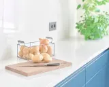 Encimeras de cocina blancas y lisas, con patatas y cebollas listas para cocinar.
