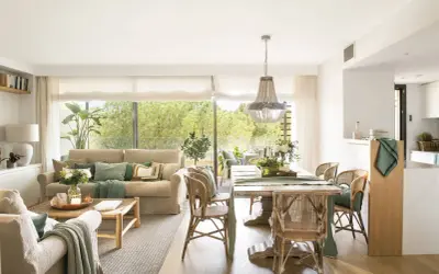 Elegante decoracion salon con sofás, mesa de comedor de madera, sillas de mimbre y gran ventanal con vistas al exterior.