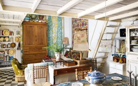 Un acogedor salón con estilo cottagecore, lleno de textiles coloridos, muebles de madera y objetos vintage.