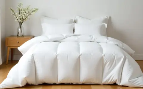 Cama impecable con edredón plumón oca blanco y cojines. Un jarrón con flores decora la mesita de noche.