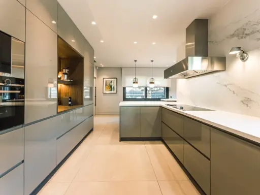 Elegantes diseños de cocinas modernas pequeñas, con gabinetes grises brillantes, encimeras blancas y electrodomésticos integrados.