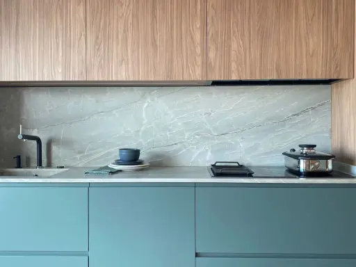 Elegantes gabinetes turquesas y encimeras de mármol gris, perfectos como colores para cocinas pequeñas.