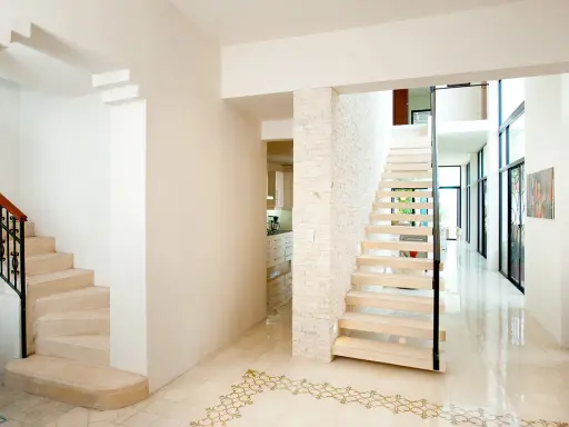 Pasillos con encanto, con escaleras de diseño moderno y clásico, y un suelo de baldosas con motivos dorados.