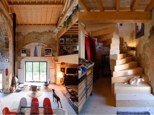 Estudio de diseño interior con escaleras de madera, perros y mobiliario ecléctico.