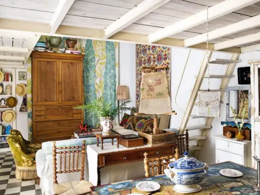Un acogedor salón con estilo cottagecore, lleno de textiles coloridos, muebles de madera y objetos vintage.