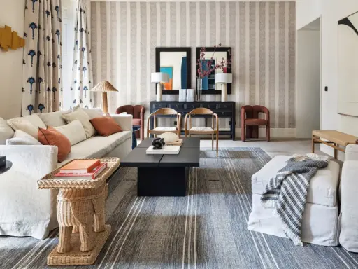 Elegante sala de estar con sofás blancos, mesa de centro negra y alfombras a rayas que complementan la decoración de la casa.