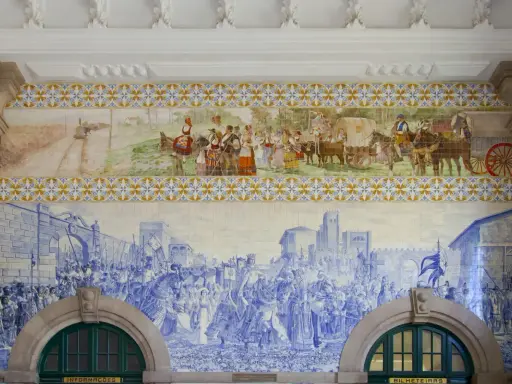 Azulejos de Oporto narran la historia: un tren antiguo, gente vestida de época y una procesión militar en azul y blanco.