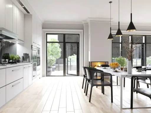 Cocina moderna con encimera de mármol negro y **suelos para cocinas sin obras** de madera clara. Mesa de comedor con sillas negras y chimenea.