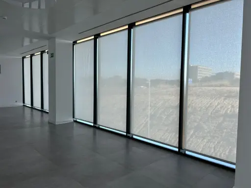 Ventanas con tejido screen que filtran la luz, creando un ambiente sereno en la oficina.