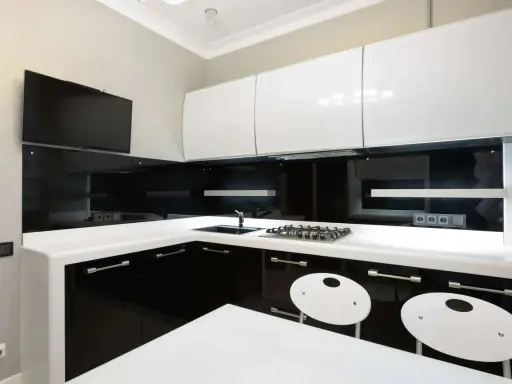 Elegantes cocinas en blanco y negro, con encimeras blancas, gabinetes negros brillantes y detalles modernos.