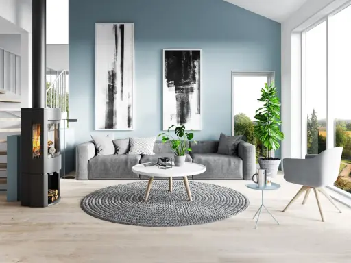 Sala de estar moderna con paredes de color azul polvoriento, sofá gris, chimenea y arte abstracto.