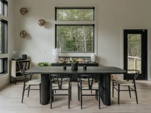 Salón moderno con mesa de comedor negra, sillas de madera y decoración de pared con esferas doradas.