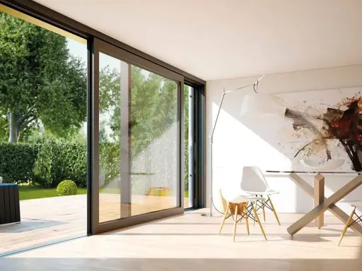 Amplias ventanas aislantes conectan un moderno comedor con un exuberante jardín.