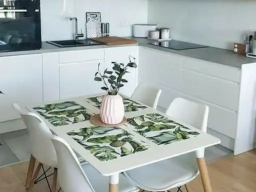 Cocinas pequeñas con mesa para comer, un espacio funcional y moderno con encimeras blancas, electrodomésticos integrados y una mesa con mantel tropical.