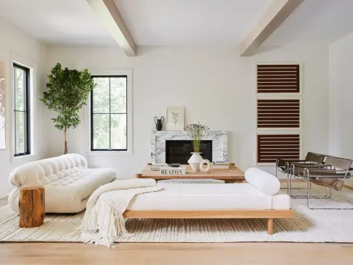 Salones blancos y madera: un sofá blanco texturizado, un diván de madera, chimenea de mármol y sillas de cuero.