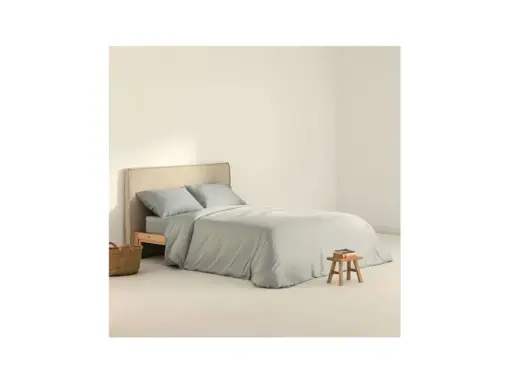 Cama con funda nordica 180x220 en tono gris claro, almohadas a juego y una cesta de mimbre al lado.