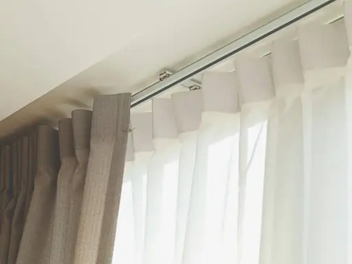Detalle de rieles para cortinas, mostrando diferentes tipos de tela y su sistema de sujeción al techo.