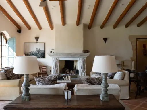 Acogedor salón comedor de casa de campo con vigas de madera, chimenea de piedra y sofás confortables.
