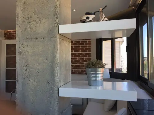 Ideas para decorar una columna en el salón: estantes blancos con Vespa y planta, ladrillo visto y hormigón.