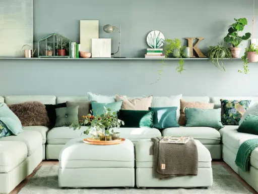Sofá modular verde agua con cojines en tonos tierra y verdes, creando un ambiente sereno.