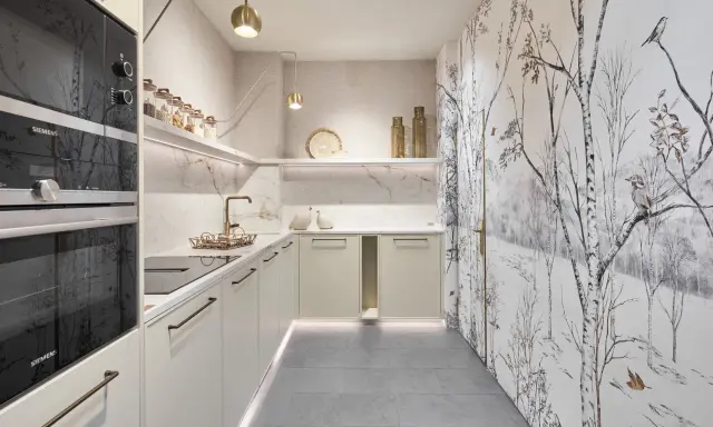 Cocinas pequeñas con encanto: gabinetes color crema, encimeras de mármol, electrodomésticos Siemens y un papel tapiz de bosque invernal.