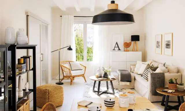 Acogedor salón estilo nórdico con sofá, sillón de mimbre, mesa de centro y estantería negra.