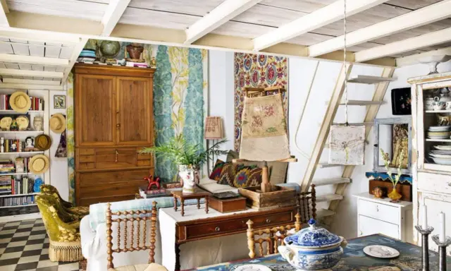 Un acogedor salón con estilo cottagecore, lleno de textiles coloridos, muebles de madera y objetos vintage.