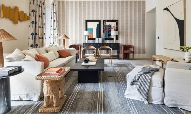 Elegante sala de estar con sofás blancos, mesa de centro negra y alfombras a rayas que complementan la decoración de la casa.
