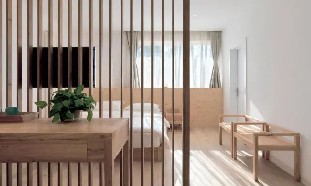 Ideas para como decorar un comedor sencillo: mesa de madera, separador de listones, cama y bancos de madera.