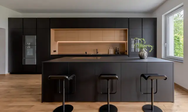 Elegantes cocinas negras y madera, con isla central y taburetes modernos.