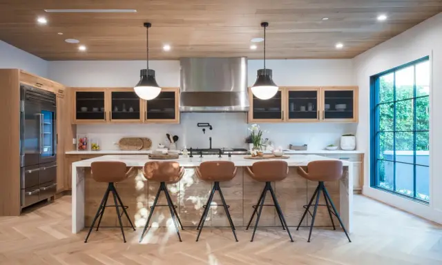 Cocina moderna con isla central y taburetes de cuero marrón. Las medidas del taburete son ideales para la altura de la isla.