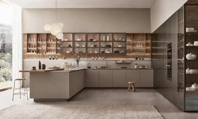 Cocina con península abierta al salón, con estanterías de madera y electrodomésticos integrados.