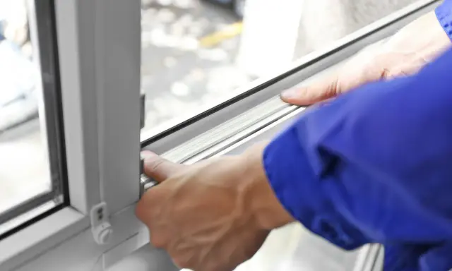 Manos ajustando el burlete para aislar ventanas, mejorando la eficiencia energética del hogar.