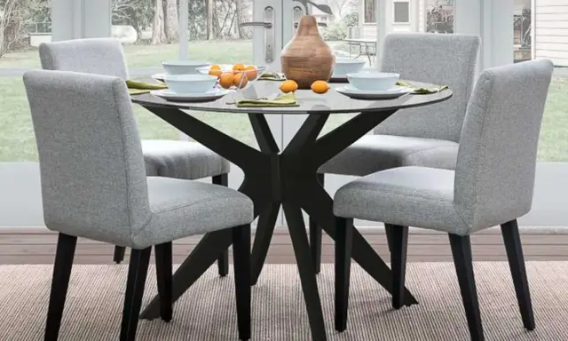 Ideas para decorar una mesa redonda: centro de mesa con jarrón y naranjas, platos y servilletas.