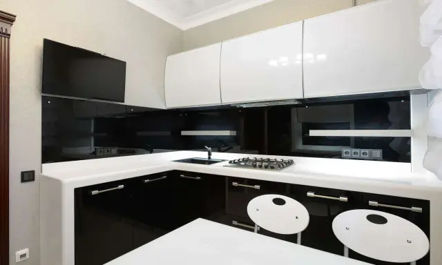 Elegantes cocinas en blanco y negro, con encimeras blancas, gabinetes negros brillantes y detalles modernos.