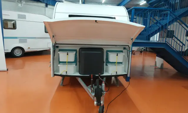 Compartimentos para decorar caravana por dentro. Almacenamiento organizado con cubos blancos y un depósito negro.