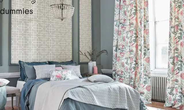 Cama elegante con ropa de cama azul y cojines florales, cortinas de proteas y papel tapiz geométrico. Un kilim Maimana aportaría calidez a este espacio.