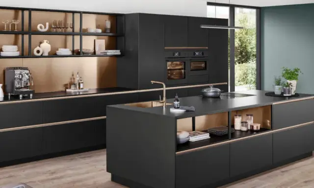Elegantes cocinas pequeñas con isla central negra, gabinetes dorados y electrodomésticos integrados.